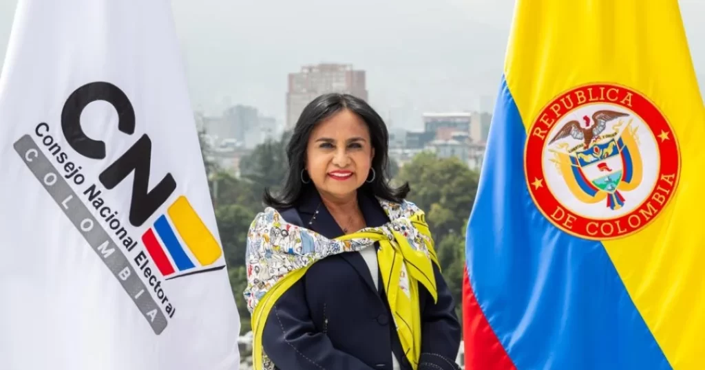 Sale la Directora del Consejo Nacional Electoral, Dora Ruth Méndez en el centro de la imagen. A la izquierda la bandera de la institución y a la derecha de bandera de Colombia